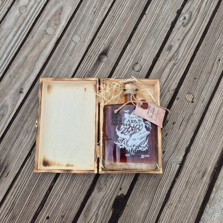 A bottle of the new Tres Hombres Captain's Choice Rum "The King" in its open wooden box.