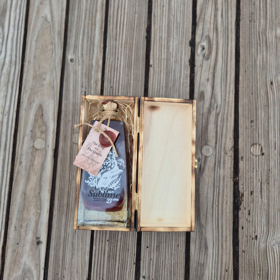 A bottle of the new Tres Hombres Captain's Choice Rum "The Queen" in its open wooden box.